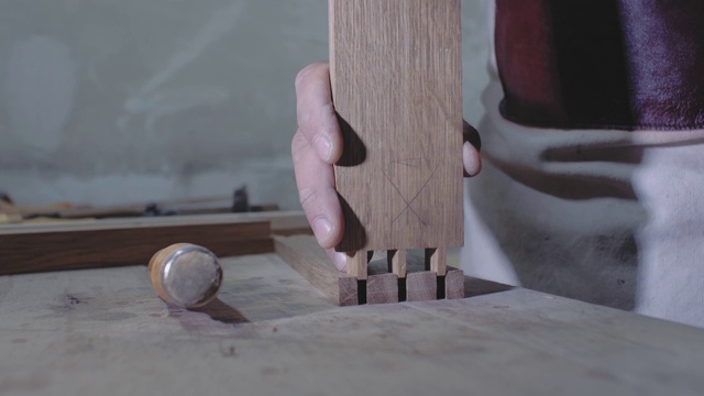 木匠用锤子将用燕尾技术制成的两个木制部件连接起来。一个木匠用燕尾榫接合的细节。4 k。4 k的视频。缓慢的运动。24帧/秒视频素材