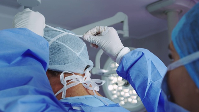 女医生在手术室帮助男医生戴口罩的特写视频下载