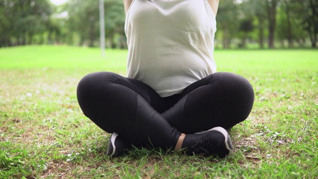 高大的女人在公园的草地上练习瑜伽视频素材