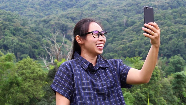 亚洲年轻女子在梯田用智能手机自拍。视频下载