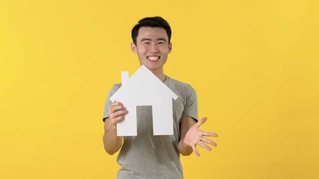 年轻的亚洲人持有房子的模型表演惊讶或高兴视频素材