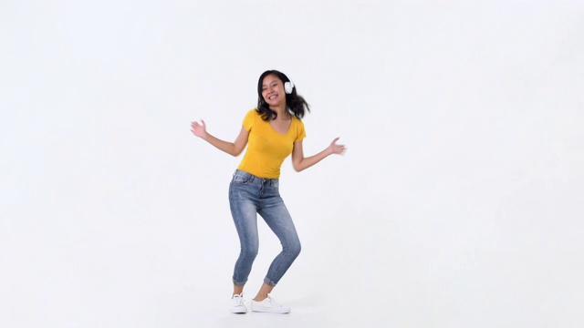 年轻快乐的亚洲女人戴着耳机听音乐和跳舞视频下载