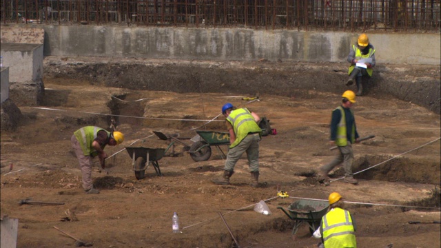 建筑工人在挖掘现场用铁铲挖掘。视频素材