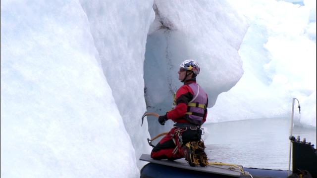 一艘船载着一个冰上攀登者到冰川的一侧。视频素材