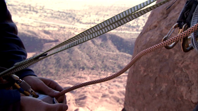 一名攀岩者在悬崖边拉起并测试安全线。视频素材