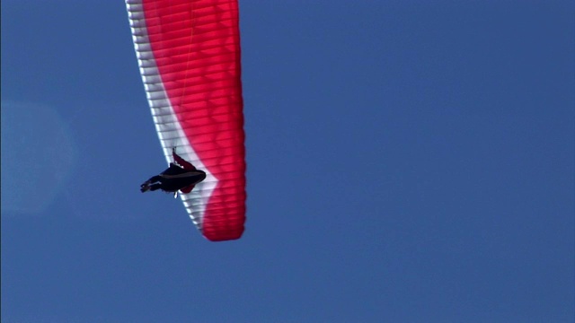 定点跳伞者在晴朗的天空中进行机动和降落。视频下载