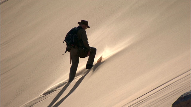 一个男人攀登撒哈拉沙漠的沙丘。视频下载