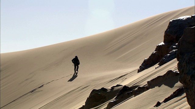 一个人独自爬上沙丘。视频下载