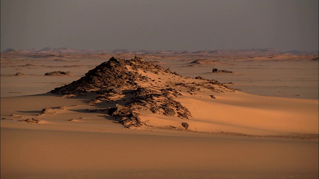 一个参差不齐的岩层耸立在撒哈拉沙漠的Gilf Kebir地区。视频下载