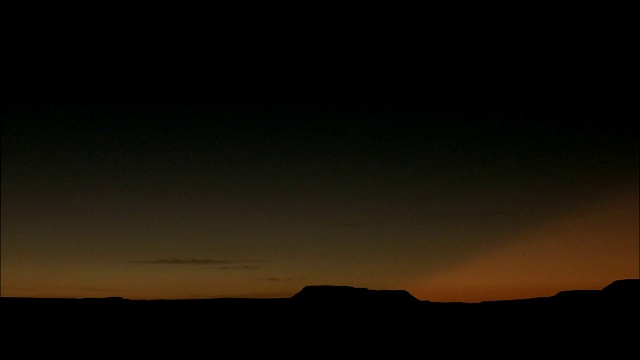 在撒哈拉沙漠，日落时地平线上出现了山脉的剪影。视频下载