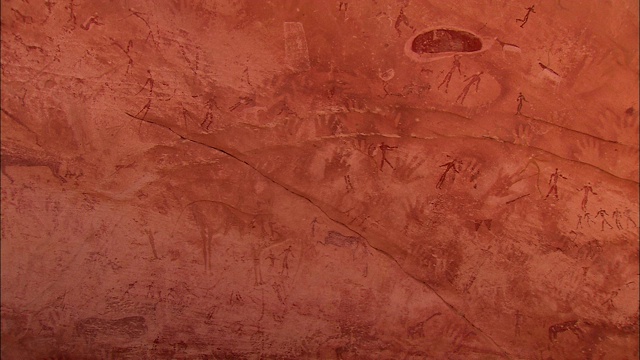 砂岩墙上重叠的岩画描绘了动物和手。视频素材