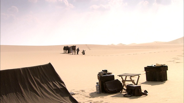 一个旅行者在靠近他的沙漠营地时遇到了一个贝都因骆驼商队。视频下载