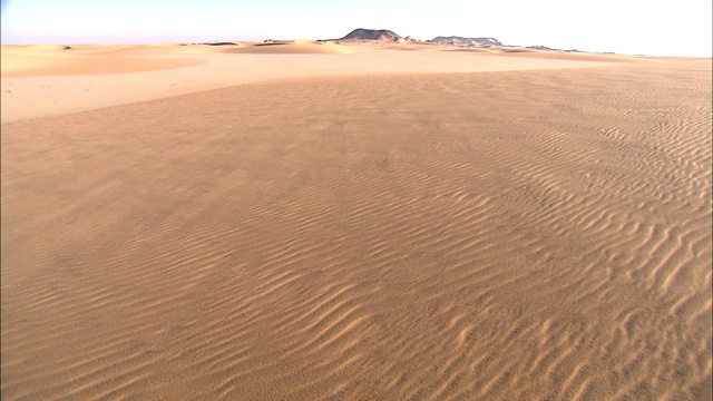 波浪形的沙子穿过地平线，延伸到岩石高原。视频下载