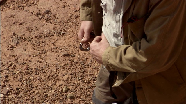 一个攀岩者从他的挽具上取下钩环并松开绳子。视频素材