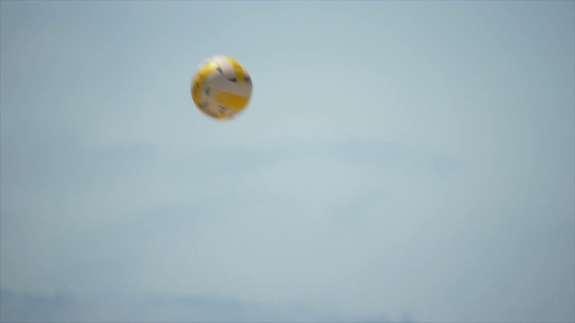 一个在空中飞过的沙滩排球，上面有网和沙子。——慢动作视频下载