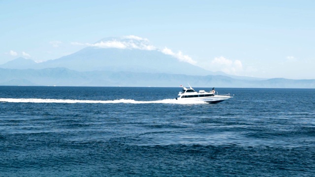 海上航行的游艇，岸上拍摄，背景是群山，慢镜头视频下载