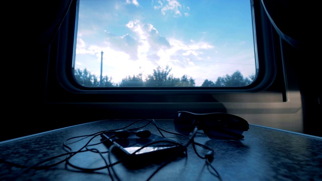 电话和眼镜放在靠近火车窗户的桌子上。视频素材