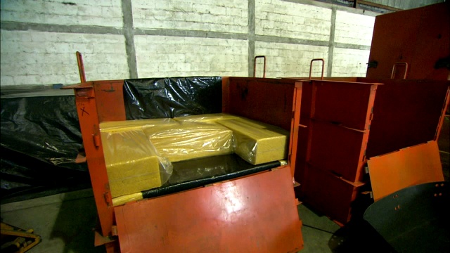 一名橡胶厂的工人搬运包裹好的橡胶块，把它们堆放在一辆手推车里。视频素材
