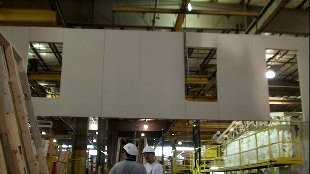 工厂工人们看着一堵墙通过一个制造的家庭工厂。视频下载