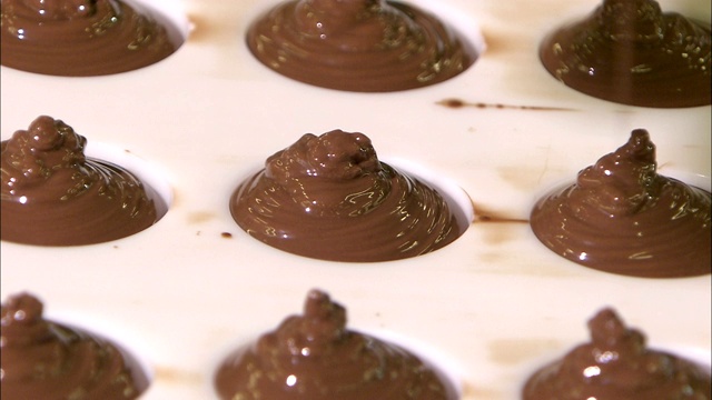 融化的巧克力源源不断地倒入纸杯蛋糕形状的托盘中。视频下载