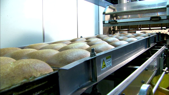 在工厂里，新鲜出炉的面包沿着传送带移动。视频下载