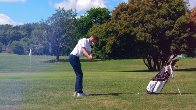一个年轻人在打高尔夫球时用球杆踢球。高尔夫球手打高尔夫，运动生活理念。视频下载
