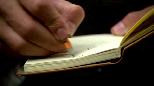 一个人用铅笔在书上写字。视频下载