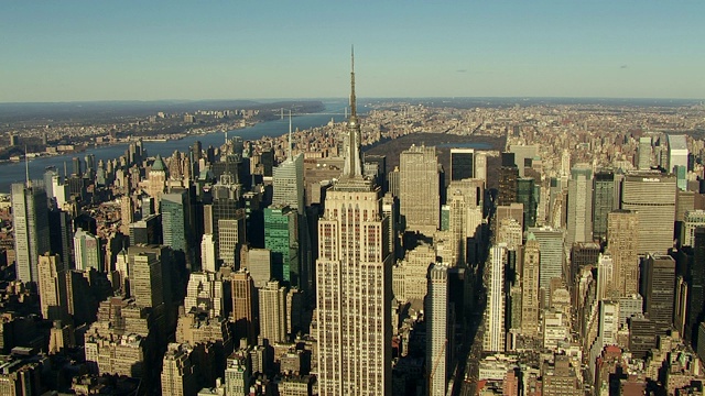 当帝国大厦俯瞰曼哈顿时，阳光反射在纽约港上。视频下载