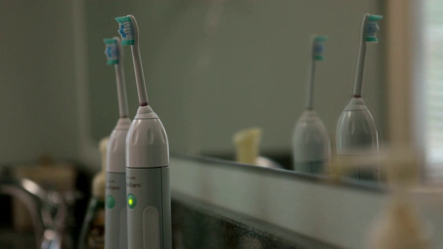 一个看不见的人把牙膏涂在电动牙刷上。视频下载