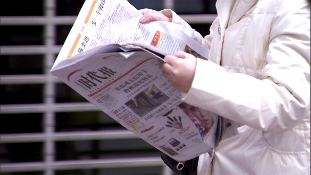 一位行人在上班路上看报纸。视频下载