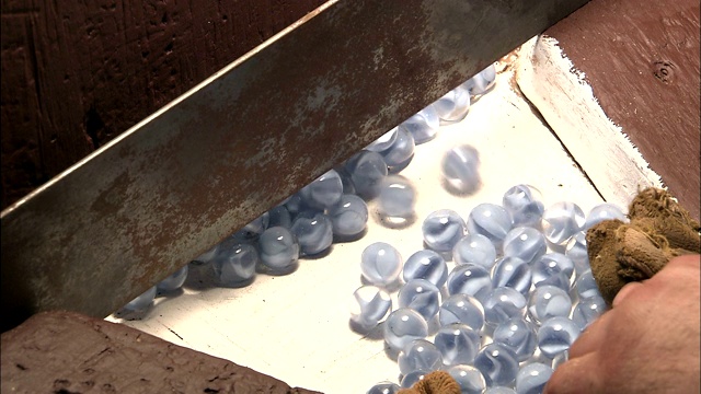 一个工厂的工人在分类透明的玻璃弹珠。视频下载