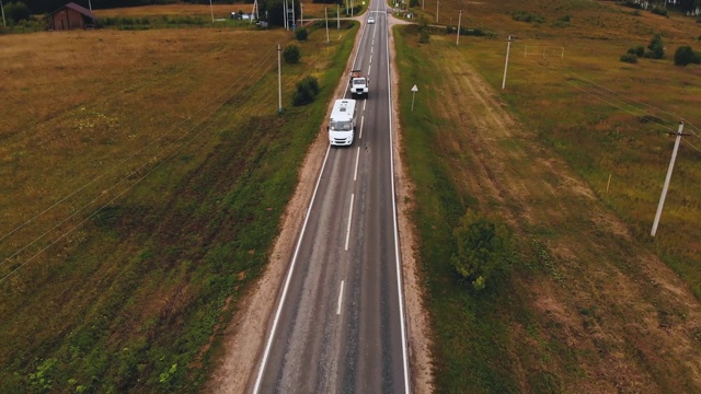 空中拍摄的白色汽车行驶在乡村道路。夏天的乡村道路上有汽车视频下载