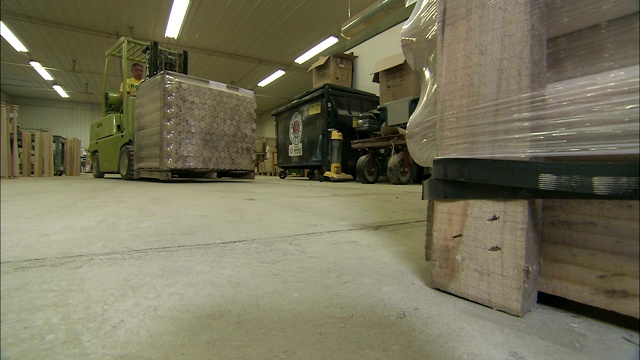 在一个棒球棒工厂的仓库里，一辆铲车搬运着一托盘的木块。视频素材