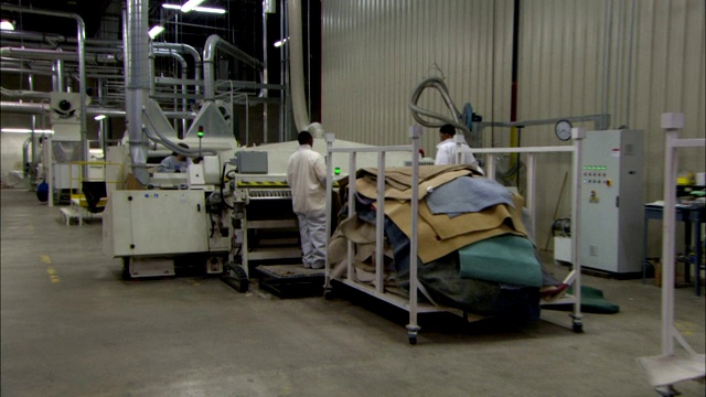 地毯工厂里，一名员工将织物从打包机中推过。视频下载