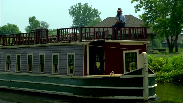 一个留着长胡子的男人在乘坐河上的渡船。视频下载