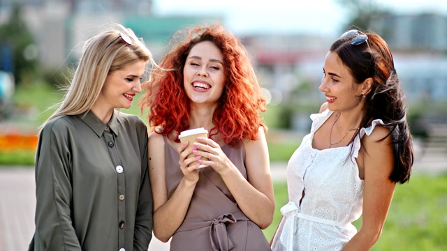 三个微笑多样化的时尚女性朋友与波浪的头发摆姿势在室外看相机视频素材