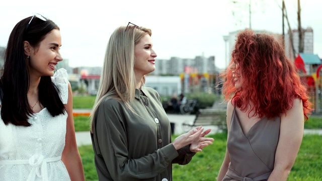 三个无忧无虑的美丽的女性朋友散步在夏季公园享受友好的交谈视频素材