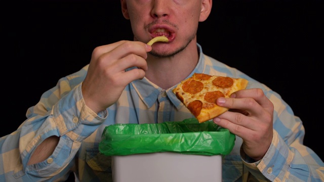 一个人在垃圾桶里吃披萨和薯条。视频素材