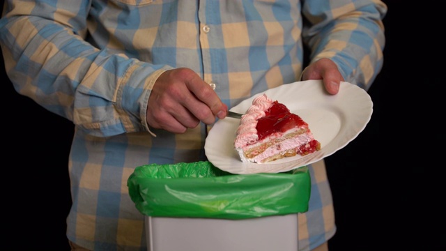 一个用盘子把草莓蛋糕刮进垃圾桶的人。视频素材