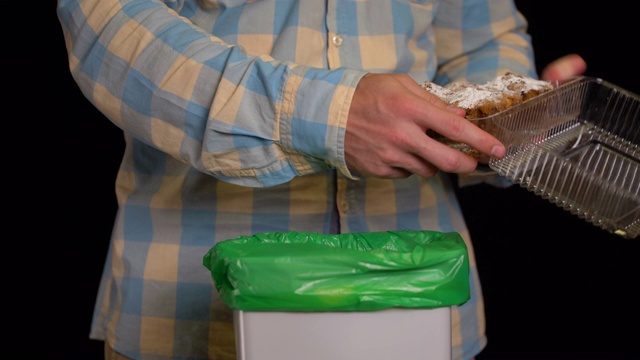 男人把纸杯蛋糕或松饼扔进垃圾桶。视频素材