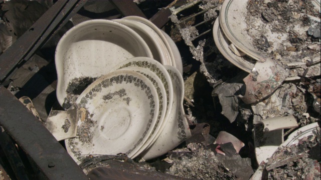 在艾尔半岛的森林大火后，扭曲的盘子躺在一幢被烧毁的建筑物的灰烬中。视频下载