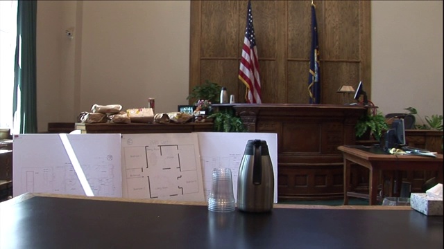 在一个空荡荡的法庭里，辅导员的桌子上放着水罐、塑料杯和笔记本。视频素材