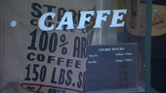 行人经过一个标有“CAFFE”字样的窗户。视频下载