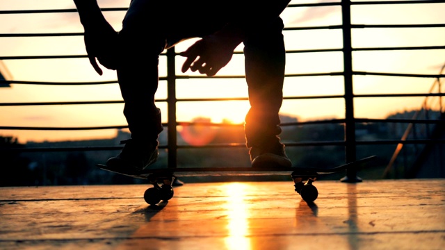溜冰者表演特技失败。在夕阳背景下，一个人在滑板上跳跃，慢动作。视频素材