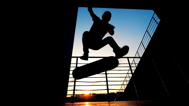 在日落的背景下，滑冰运动员在滑板上跳跃，慢动作。视频素材