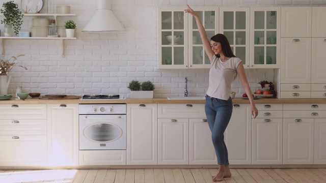 快乐无忧无虑活泼的女孩独自在现代厨房内部跳舞视频素材