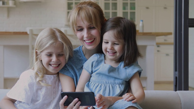 快乐的妈妈和小女儿在智能手机上看动画片视频素材