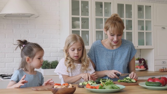 有趣的孩子和兄弟姐妹一起帮妈妈切新鲜蔬菜沙拉视频素材