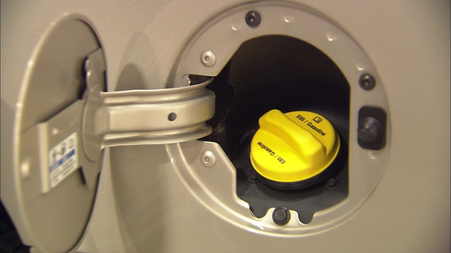 一个亮黄色的乙醇气盖盖在汽车油箱的开口处。视频下载