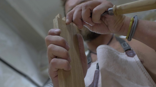 木匠手里拿着凿子，在木头上雕刻一个燕尾榫。木工加工木板。4 k。4 k的视频。缓慢的运动。24帧/秒视频素材